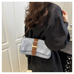 Detail of vintage baguette bag showing light blue washed fabric and brown leather strap