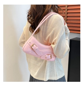 Detail of pink croc-embossed underarm bag with buckle decoration on model