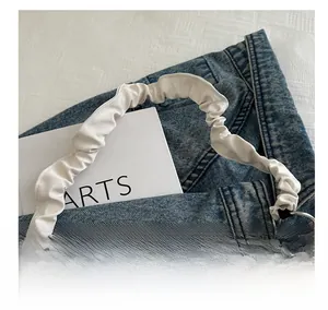 Detailed close-up of white ruched cloud-style handle with silver metal rings on a beige tote