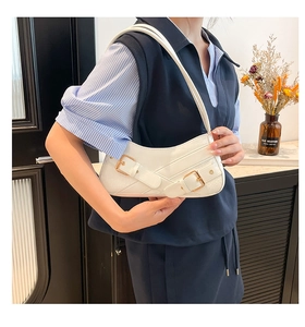 Detail of white baguette bag with crocodile pattern and golden metal buckle accents