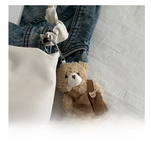 Close-up of cute plush bear charm with brown corduroy overalls and silver ball chain