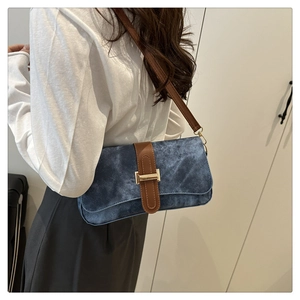 Detail of vintage blue textured fabric baguette bag with brown leather strap and gold buckle