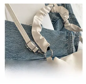 Detail of white matte leather bag featuring a ruched cloud strap and silver metal buckle