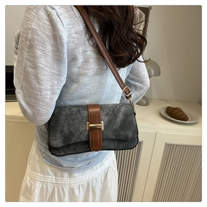 Close-up of a vintage grey suede handbag with brown leather strap and gold buckle detail