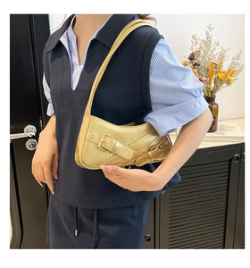 Detail of golden crocodile embossed underarm bag with metal buckle on leather strap