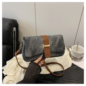 Detail of grey shoulder bag with brown leather trim and golden H-shaped buckle closure