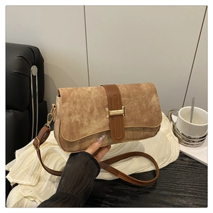 Detailed close-up of brown suede shoulder bag with gold buckle and adjustable strap