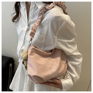 Detailed view of pink shoulder bag with cartoon bear print and soft plush bear charm