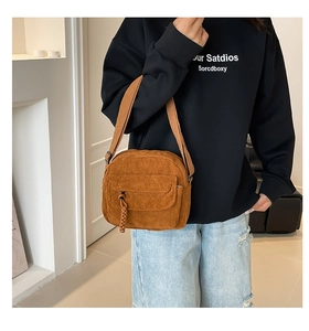Brown corduroy crossbody bag with adjustable canvas strap worn by model on blue jeans
