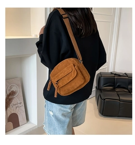 Detail of caramel corduroy crossbody bag featuring a front pocket and woven zipper pullers