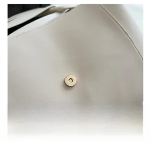Detailed close-up of cream leather tote bag featuring a matte gold magnetic buckle