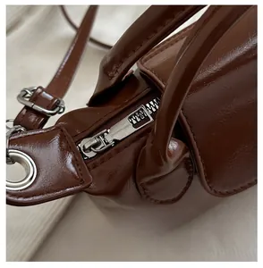 Detail of brown faux leather texture with silver zipper and reinforced stitching on handbag