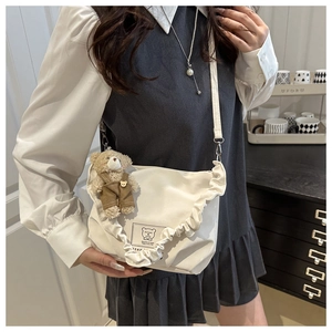 Detail of white ruffled canvas shoulder bag with cute bear pendant and cartoon patch