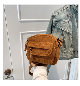 Detail of brown corduroy crossbody bag featuring woven zipper pull and adjustable strap
