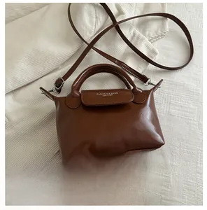 Brown leather handbag shown next to a smartphone to demonstrate its compact size