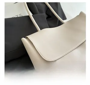 Close-up of the beige tote bag showing high-quality lychee leather texture and fine stitching