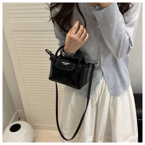 Détail d'un sac bandoulière noir brillant en cuir PU avec texte blanc et bandoulière