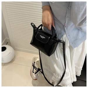 Détail d'un mini sac cabas en cuir verni noir avec poignées et bandoulière amovible