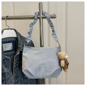 Detail of light blue tote bag with cute bear print and plush charm on a hanger
