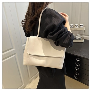 Minimalist beige leather tote bag with a sleek flap design shown on a model for daily use
