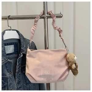 Detailed view of pink shoulder bag featuring a bear charm and pleated handle