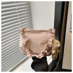 Pink ruffled tote bag with bear print and plush charm against a minimalist interior