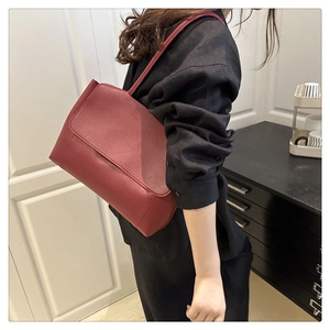 Side view of dark red leather tote bag being worn as an underarm shoulder bag
