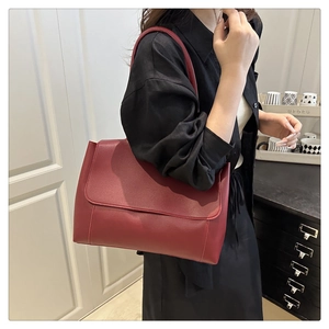 Detail view of the deep red shoulder bag with fine stitching in a lifestyle setting