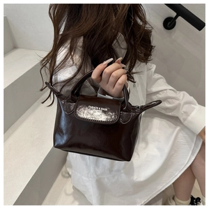 Détail d'un sac à main marron foncé montrant la finition cuir et la poignée chic