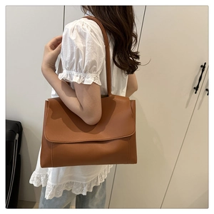 Detailed close-up of brown faux leather tote bag with elegant matte finish on model