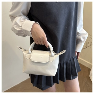 Gros plan détaillé d'un mini sac blanc avec poignée courte et rabat à fermeture aimantée