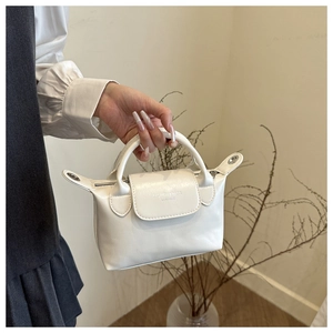 Close-up of minimalist white hobo bag showing faux leather texture and silver hardware