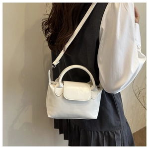 Détail d'un petit sac à main blanc minimaliste porté en bandoulière par un mannequin