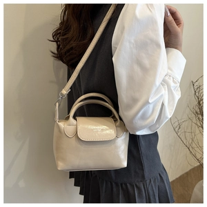 Détail du sac à main blanc crème montrant la bandoulière réglable et le rabat texturé
