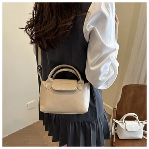 Dettaglio di una mini borsa a tracolla chic in pelle PU crema con scritte alla moda