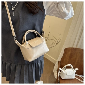 Close-up of the beige pebble leather dumpling bag with top handles and adjustable strap