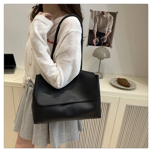 Detail view of a black matte leather tote bag styled in a minimalist interior setting
