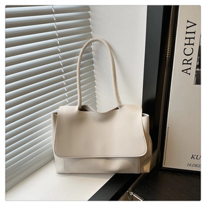 Close-up of cream minimalist leather tote bag with flap and handle on window ledge