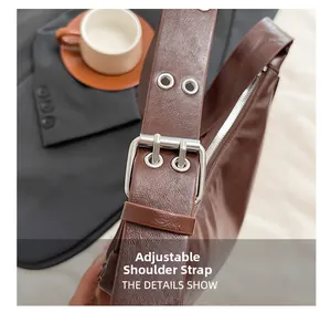Detail of adjustable leather shoulder strap with silver buckle on brown dumpling bag