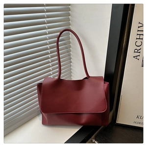 Detail view of burgundy leather tote bag featuring sleek flap closure and slender shoulder straps