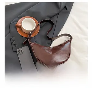 Detail of dark brown crescent saddle bag with textured leather and adjustable strap