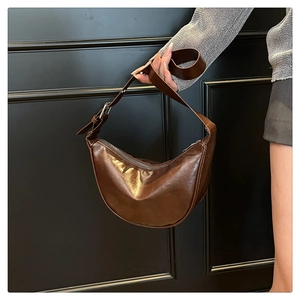Detail of dark brown semi-moon shoulder bag in glossy patent leather with silver zipper