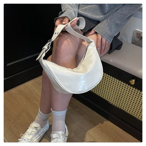 Lifestyle view of a cream white crescent hobo bag with adjustable strap on a model