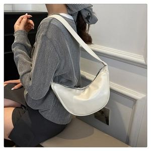 Detail of white leather crescent shoulder bag showing textured material and zipper closure