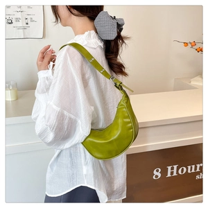 Detail of avocado green crescent hobo bag with adjustable silver grommet shoulder strap