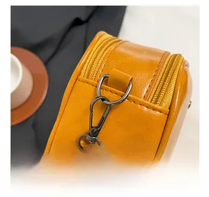 Detail of yellow leather crossbody bag with gunmetal hooks and double zipper structure