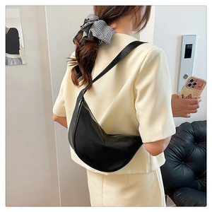 Side view of a black crescent shoulder bag on a model showing size and matte texture