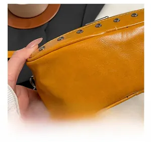 Macro view of mustard yellow pebbled leather with silver studs and precision stitching