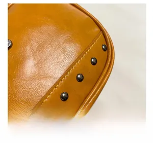 Detail shot of orange leather bag with metallic rivets and professional stitching