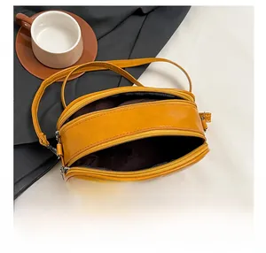 Detail showing two zipper compartments and spacious interior of yellow crossbody camera bag